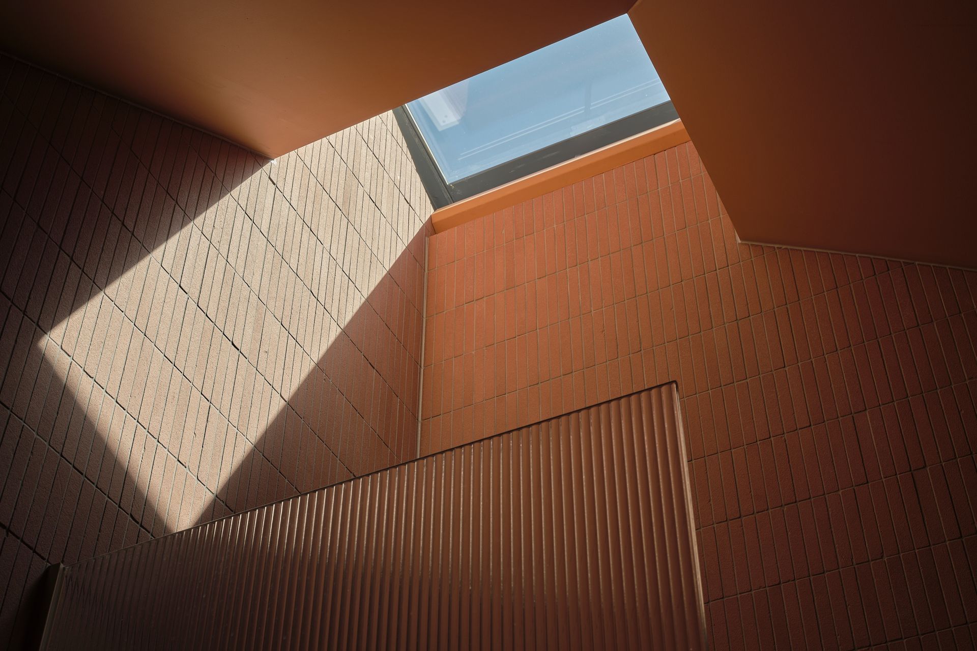 Sunlight entering through a skylight above terracotta-coloured tiles in the Turnbull bathroom.