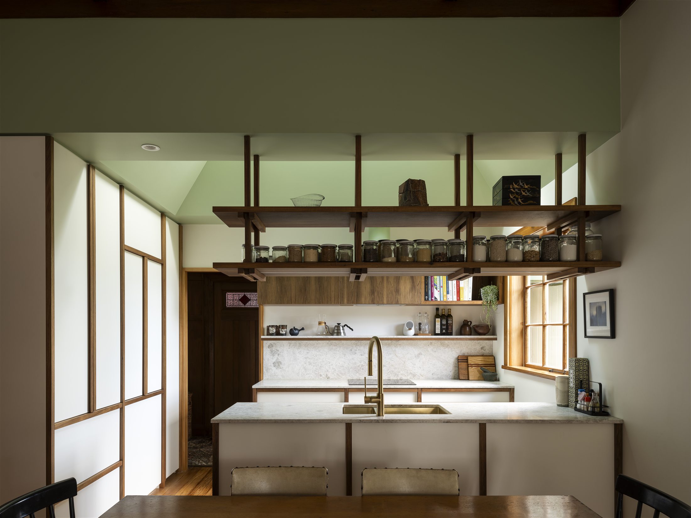 Open timber shelving over the kitchen bench at Woodford, viewed from the adjoining dining space.