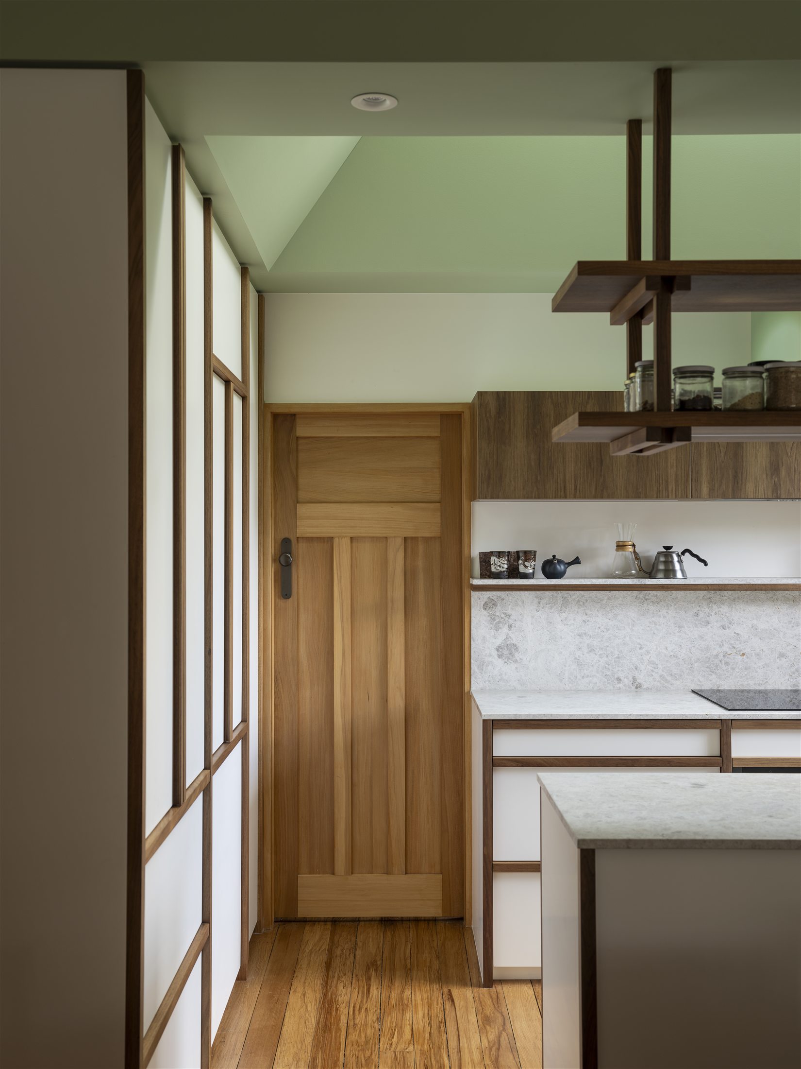 Timber door, glazed screen and finely detailed kitchen cabinetry beneath the green lightwell at Woodford.